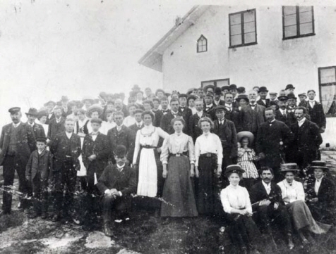 En större grupp vuxna kvinnor och män som står framför en byggnad