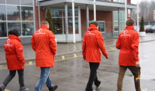 Fyra personer med röda jackor som går på en väg