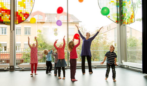 Barn och en vuxen dansar med ballonger