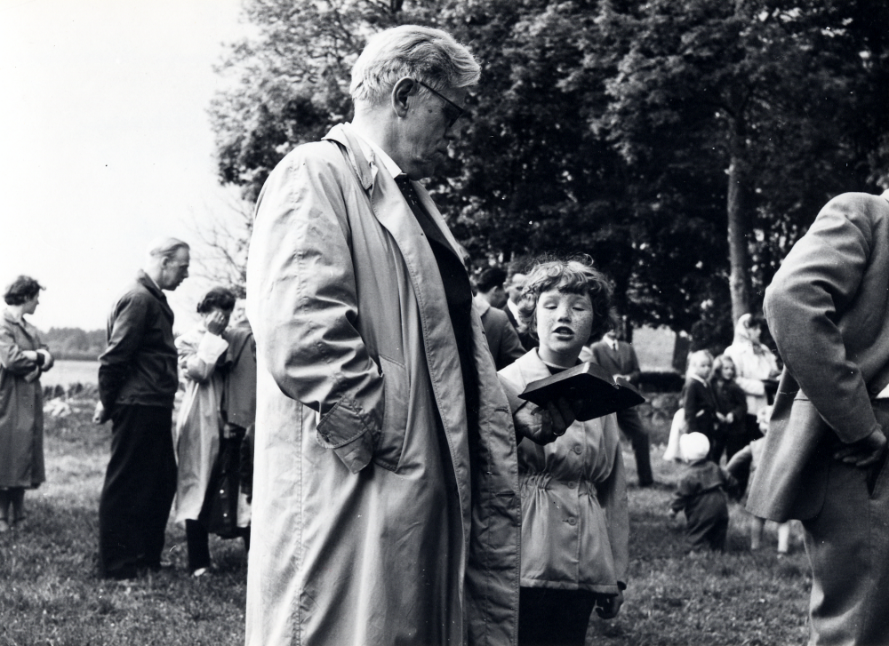 Midsommarfest  vid  Korsbacken  nedanför  Vallentuna kyrka  I förgrunden står kyrkoherde  Sven Vängby  och sjunger tillsammans med en flicka och tittar i samma psalmbok