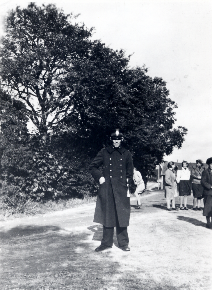 Riksmarschen i Angarn.  I bildens mitt står fjärdingsman Helmer Bergström. Långt i bakgrunden skymtar småskolan i Angarn.  Bland flickorna syns i vit jacka Valborg Nilsson och i randig kavaj Svea Sjöman.  Damen i hatt är ev fru Lindersson.  Marschen ägde rum 1941 och var ett säreget arrangemang för att höja medborgarandan.  Män marscherade 15 och kvinnorna 10 km inom en bestämd tid.  Poängen räknades i relation till Sveriges och Finlands folkmängd. Många deltog i traditionell Sverige-Finland friidrottsanda.  Finlands president och statsminister deltog under stor mediebevakning. Sammanlagt deltog 1 507 111 finländare  och vann över Sverige i detta evenemang som var säreget i hela världen.  Man hade lyckats stärka gemenskapsandan.