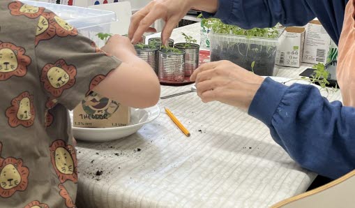 Barn och pedagog planterar växt.