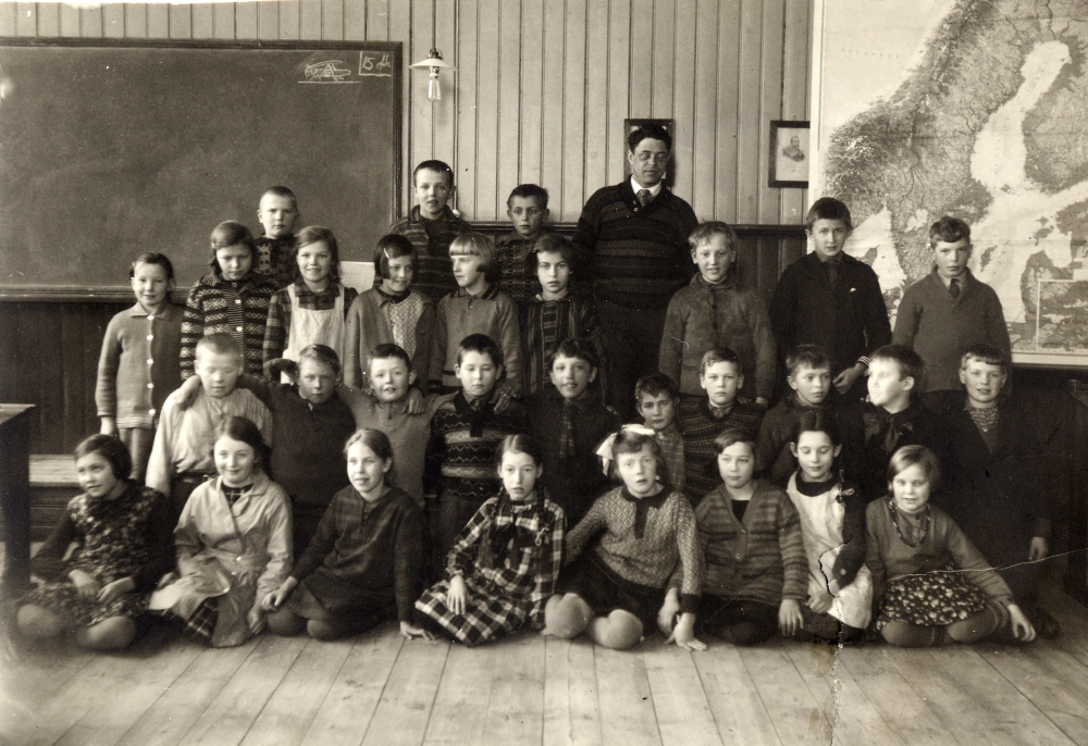 Avgångsklassen i Hjälmsta skola 1933. Läraren Josef Andersson tillsammans med skolbarnen i klassrummet i Vita skolan. Golvbeläggningen är träplank.                       
En del skolelever återfinns på en kamratträff 1958 se 040 03  02: 020, samt 397 och 398