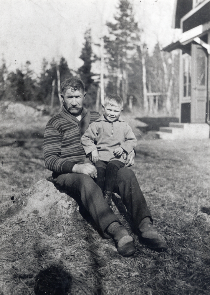 Erik "Gallmossaren" Eriksson med dottersonen Karl-Henry Karlsson i morfars knä.  Karl-Henry föddes 1928 och spelade bl a ishockey i VBK med smeknamnet "Kalle-Stämmis".  Huset till höger är Gallmossen