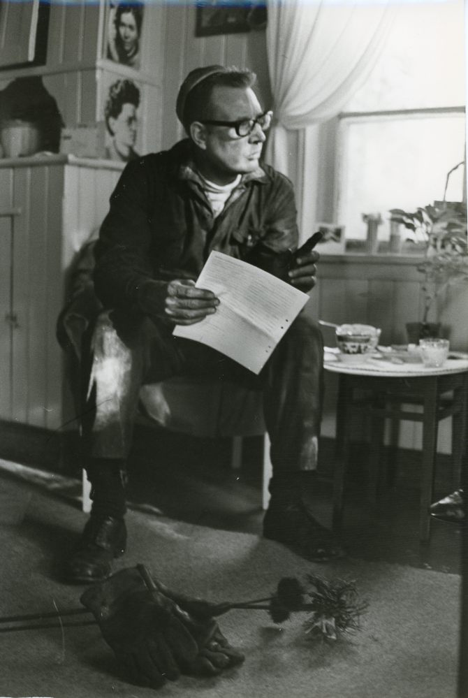 Skorstensfejarmästare Carl-Erik Edlund har en kaffepaus. Framför honom på golvet ligger arbetshandskarna och ett av hans verktyg.