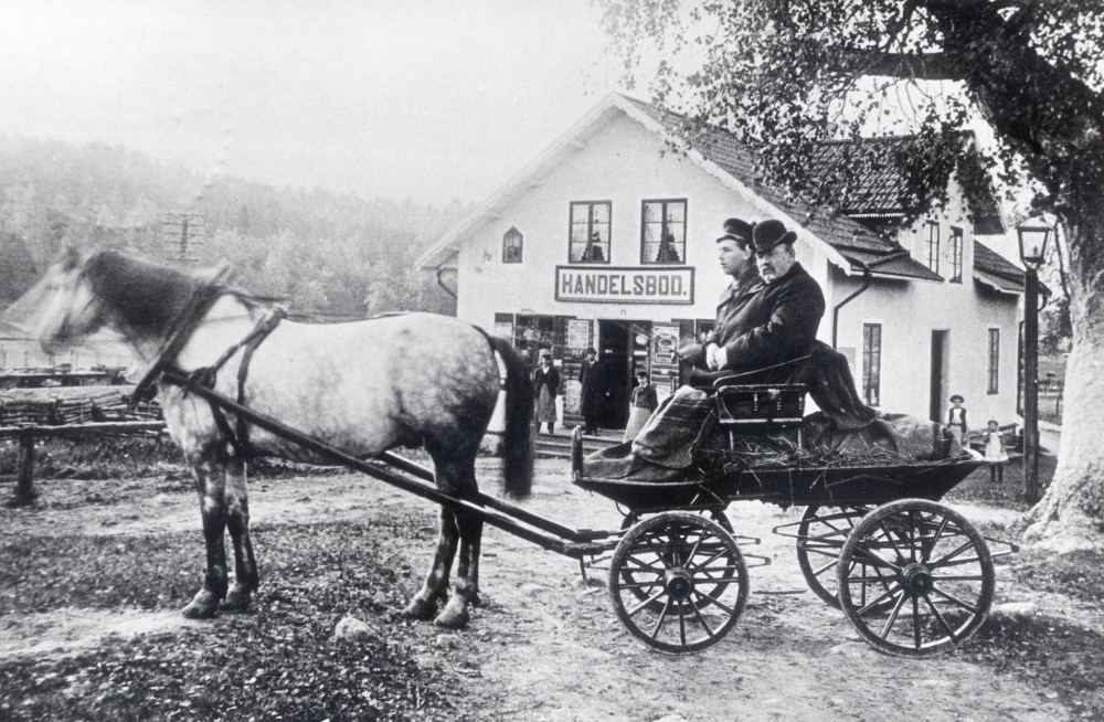 Handelsboden Österlid var den äldsta handelsboden i Kårsta, sannolikt byggd samtidigt med Roslagsbanan omkring 1885. Rörelsen hade flera idkare. Fastigheten brann ner 1942 men byggdes upp på nytt av Ebba Staff (ägaren Arvid Staff dog i början av 1940-talet). Ebba drev affären ensam fram till 1965. Huset är nu bostad för familjen Staff. På bilden syns en häst som drar en vagn med två personer. Vallentunabilder nr 61. Backa gård ägde Österlid till 1965. Familjen Staff hyrde huset från 1935 till 1965, då köpte Eivy och P-O Staff fastigheten och byggde om den 1969-70.