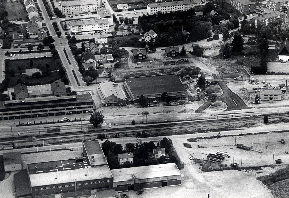 Flygfoto  över  Vallentuna centrum  med  Tellus-Maskin  i förgrunden  Roslagsbanan   och centrums förvaltnings- och affärshus i bildens mitt.  Ännu finns  Tvillingvillorna  kvar, men fyrkanter mellan dem och det nybyggda, ännu ej färdiga  Domus  visar att gjutningsarbeten för förvaltningshuset  Tärningen  snart skall påbörjas