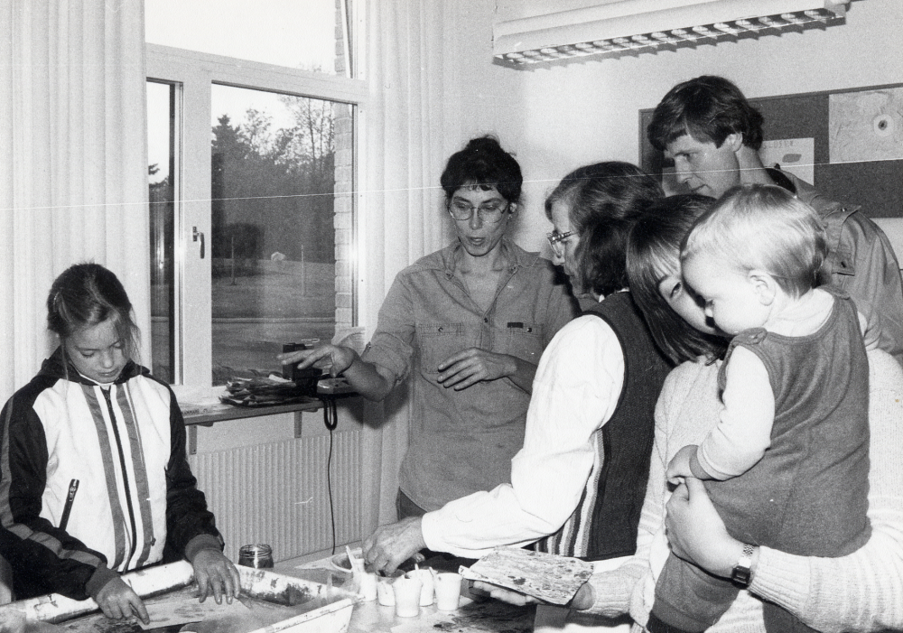 Svenska boktryckerikonstens 500-årsjubileum 1983 Boken fyller år uppmärksammades i Vallentuna bibliotek med utställningar och program. Här visar Eva Rahmqvist hur man marmorerar papper i ett vattenbad. Åskådare i glasögon är Eva Kristiansson och t h om henne Lasse Widén
