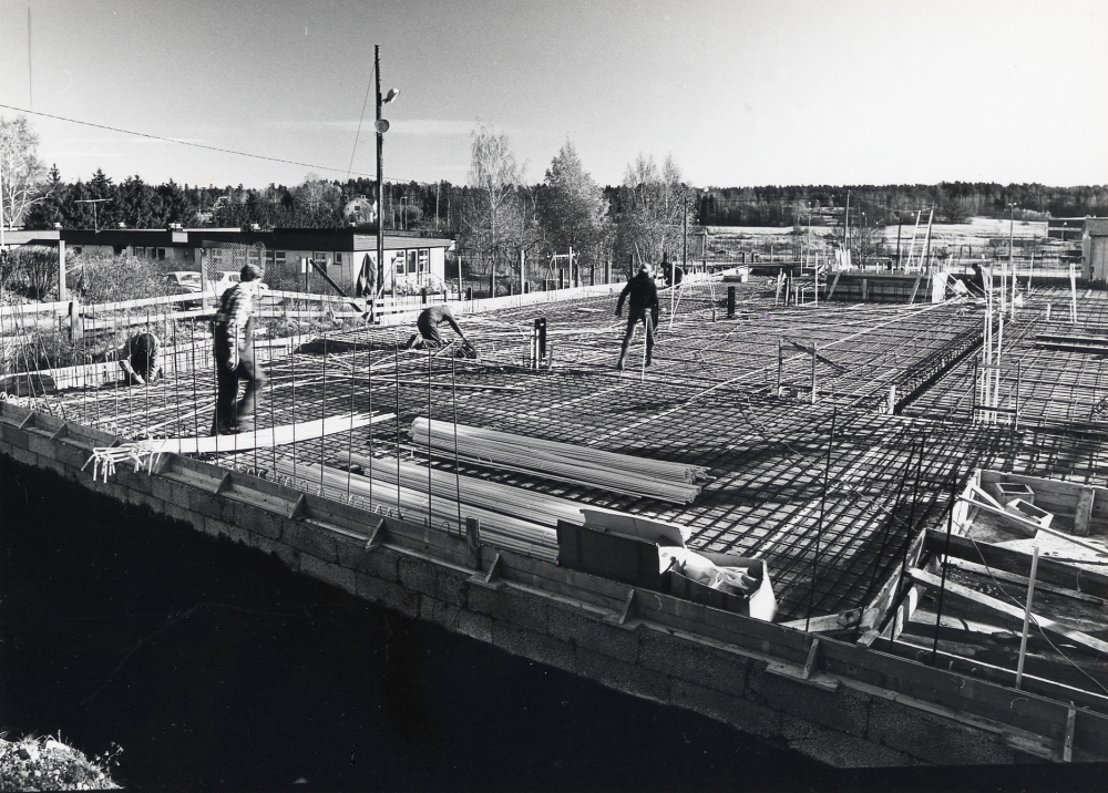 Pingstkyrkan i Vallentuna under byggnad hösten 1978. T v syns daghemmet Videgården. På bilden arbetar man med armeringsjärn inför gjutning av grunden