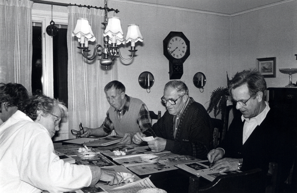 Studiecirkeln Ejnar Carlsson - en man och hans bilder arbetar hemma hos Sven Billersjö på Billsta gård i Frösunda. Bonden Ejnar Carlsson, arrenderade tillsammans med sin bror Emil Frösunda prästgård, testamenterade sina fotografier till Frösunda hembygdsförening. I samarbete med Studieförbundet Vuxenskolan har man arbetat med att ordna fotosamlingen. Vid bordet sitter på vänster sida  Ulla Öhrlund och skymd Kerstin Mannerfeldt, på höger sida fr v Stig Öhman, , Harry Öhrlund och Olle Wredh.  Alla deltagarna petar bort den tejp fotografierna är fästa med i albumen.  I stället för tejp använder man arkivbeständigt lim