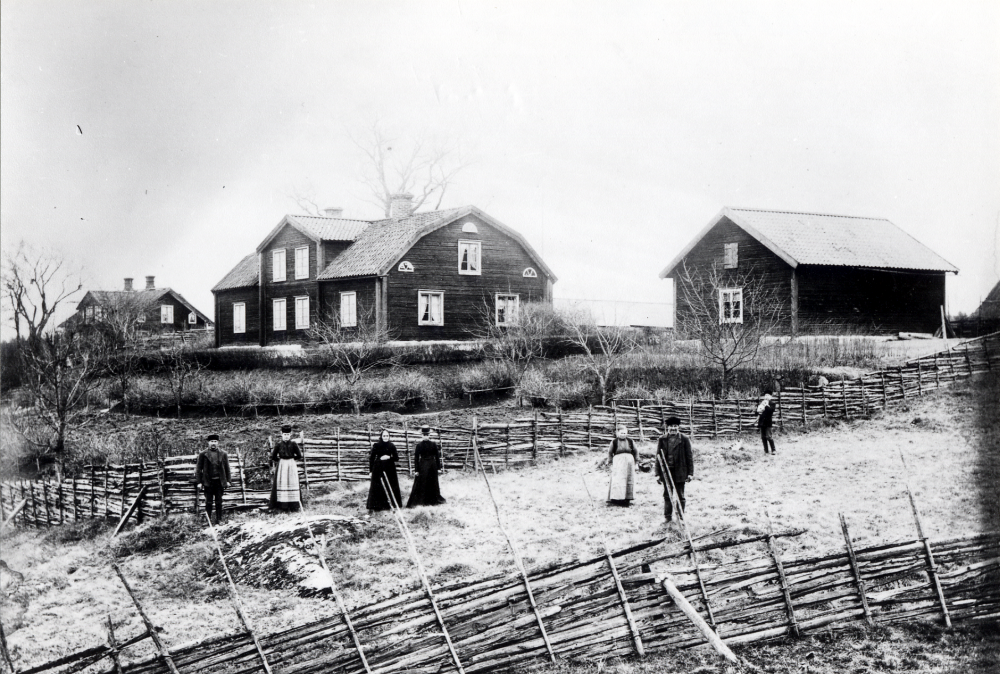Nedanför Södergården i Solsta står f v Valentin Nilsson, Berna Nilsson, Charlotta Persson (1838-1920) och dottern Elin Persson (1866-1944). Mor och dotter var gårdens ägare. Den lilla pojken med katten är Ejnar Söderberg född 1894. Huset längst t v är Norrgården i Solsta som brukades av Axel Wahlström och hans hustru Augusta