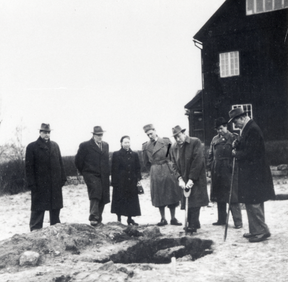 Första spadtaget till nya Centralskolan i Vallentuna.  Fr v står Erland Eriksson, okänd, Anna-Brita Dahl, Petter Nordin,  kommunalnämndens ordförande Gustav Nilsson håller i spaden, Josef Andersson och okänd.  I bakgrunden syns Röda skolan, byggd 1925.  Anna-Brita Dahl berättar: " Arbetsutskottet i skolstyrelsen öppnade sitt sammanträde den dagen med att sätta spaden i jorden för den nya Hjälmstaskolan."