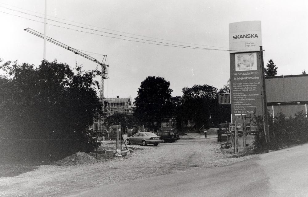 Byggarbetsplatsen i de s k Trädgårdskvarteren vid Mörbyvägen i hörnet av Källvägen.  Byggherre är Skanska.  Områdets lägenheter kallas Runhällen.  Här syns Mörbyvägens nya sträckning längre västerut mellan de nya bostadshusen med 54 bostadsrätter