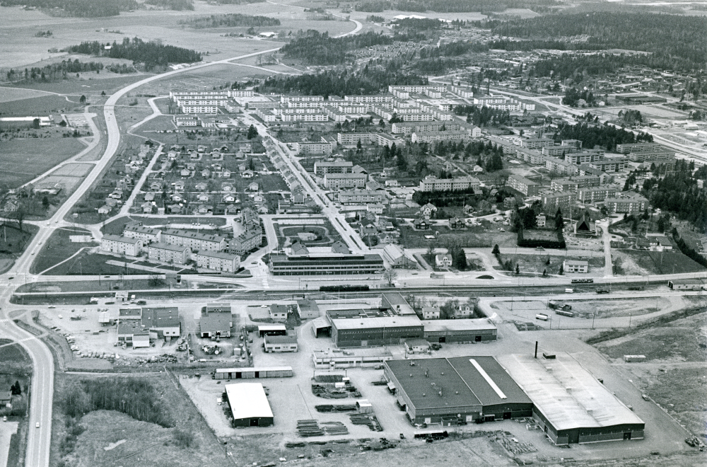 I bildens mitt syns nedifrån och upp Tellus Maskin AB, ett tåg på stationen, Tunahuset, Gamla kommunalhuset med tillhörande park, Allévägen och Sörgården. Bilden är tagen den tolfte maj.