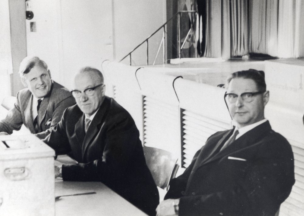 Vid kommunalvalet 1962 i kommunalhusets sessionssal sitter fr v Tage Berglund, Västanberga, Thitus Hahn (Lengquist och Hahns trävaruindustri) och Erland Eriksson.  Eriksson handlade med säd och kallades därför "Sädes-Erland".  På bordet står en låda att stoppa valkuvert i