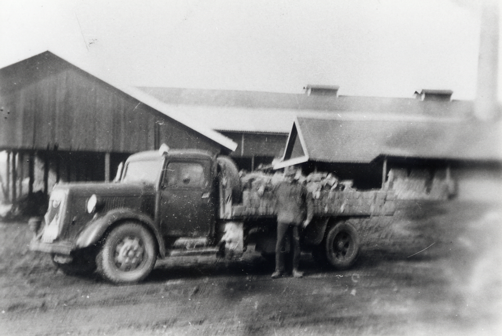 Bertil Söderberg levde 1909-1981 och hade åkeri i Vallentuna. Bostad och garage fanns i Sannalund, nuvarande Olsborgsvägen 42.   Här sitter han vid ratten i en Volvolastbil  vid Åby tegelbruk där flaket lastats med murtegel.  Bertil Söderberg körde från 1928 tegelprodukter från Åby tegelbruk, men senare även från Vallentuna tegelbruk,  till olika byggen i Stockholmstrakten och i Vallentuna.  Bertil sitter själv vid ratten (enligt påskrift på originalfotografiets baksida) och bredvid flaket står  utskjutare Nils Hansson
