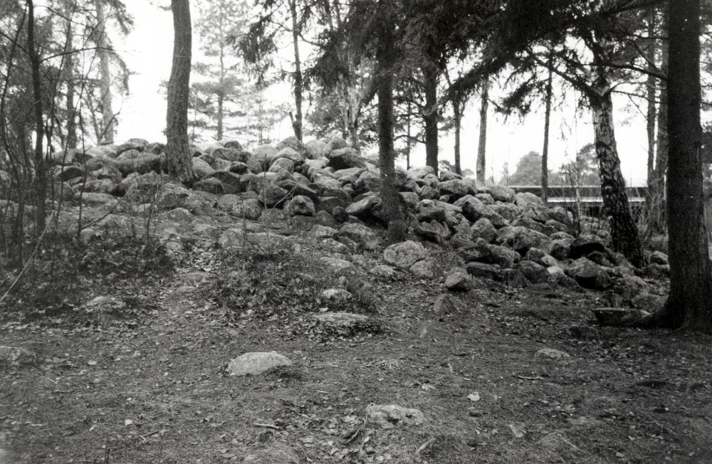 Bronsåldersgrav öster om Ekebyskolan i Vallentuna.  Längst upp t h syns skolans tak.  En gångstig passerar graven mellan Fornminnesvägen och skolan.  Vid undersökning 1966 innan Ekbeyskolan byggdes, utgrävdes ett antal  gravar  från  yngre järnåldern  (400-1050 e Kr). Dessa innehöll förutomkol och brända ben, pärlor, järnnitar, järnspikar, krukskärvor, en kniv, en nål av järn samt fragment av vävtyngder. Dessutom undersöktes en anläggning för primitiv järnframställning, en s k smältgrop