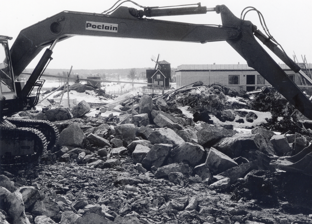 Ålderdomshemmet Väsbygården byggs på den gamla Väsby gårds mark.  Totalentreprenör är byggnadsaktiebolaget ABACUS.  K E Karlsson är elinstallatör.  Under grävskopans arm syns Väsby kvarn och kvarnvillan.  En vinge på kvarnen är skadad av den svåra stormen i november 1969.