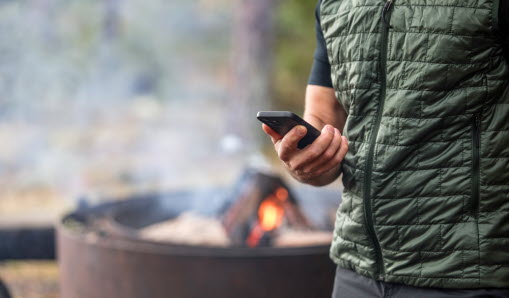 Utomhusgrill och en man som håller i en mobiltelefon