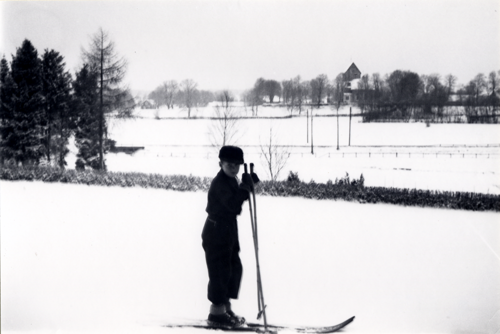 Jerker Andersson ?? med skidor utanför Hjälmsta skola. I bakgrunden syns Vallentuna kyrka