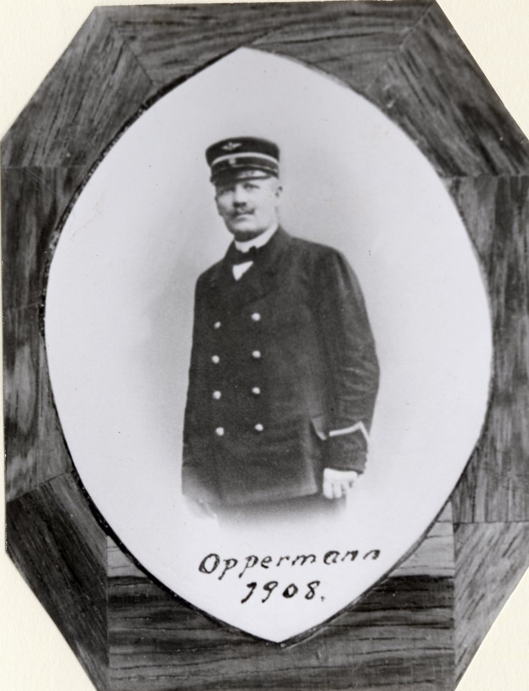 Del av tavla med stationsföreståndare vid Vallentuna järnvägsstation Oppermann 1908. Foto monterat i trä. Tavlan hängde i expeditionen i stationshuset som revs 1971. Tavlan hänger nu i Åbybergskyrkans cafeteria Nyponstigen - Nypåstigen. Uppgift om fotoår saknas.