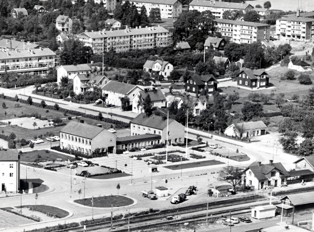 Flygfoto  över  Vallentuna centrum  I förgrunden i bildens mitt  Vallentuna kommunalhus  med torget framför. I förgrunden t h  Vallentuna järnvägsstation  med  godsmagsin  I bildens mitt  Allévägen  Flerfamiljshus byggs med adress Allévägen och  Sommarvägen  Ovanför stationshuset har Tibells affär rivits. På dess plats skall ett nytt  Konsum  byggas