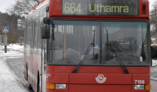Framsidan av en röd buss om kör längs med vägen.