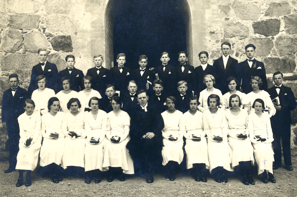 Konfirmation i Vallentuna kyrka. I mitten kyrkoherde Sven Vängby.  Övre raden fr v Folke Noacksson, Rune Ahlin, Gustav Söderlund, Börje Karlsson, Gösta Blomdahl, Gauffin, Magnus-Hans Gauffin, okänd.  Rad 2 fr v okänd, Britta   Appelgren, okänd, okänd, Gösta Pettersson Heidmark, Ingvar Eriksson, okänd, Sture Skagerlind, Maja Nordström, Karla Broman, Greta Mörk och Karl-Erik Johansson.  Nedersta raden fr v okänd, Britta Staaf, Elsa Olsson, Britta Larsson, Berta Wigren, Sven Vängby, okänd, okänd okänd, okänd, Märta Eriksson.