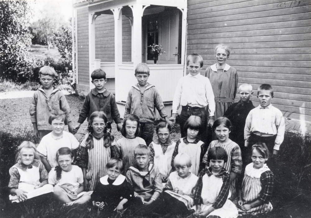 Lärarinnan Maria Nyberg tillsammans med skolbarnen utanför Salby skola i Ekskogen.  Övre raden fr v Bertil Eriksson, Karl-Erik Ahlgren, Anders Söderberg, Gösta Nyberg, Gustav Andersson och Kurt Johansson. Knästående fr v Lizzie Axbom, Margit Svärd, Ester Åman, Anny Andersson, Anna-Lisa Karlsson, Greta Nyberg.  Sittande längst fram fr v Karin Andersson, Gunhild Eriksson, Arne 'Lill-Arne' Eriksson, Torsten Björklund, Margit Karlsson, Elsa Lundin och Karin Fredriksson