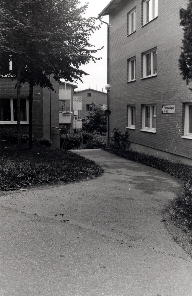 Flerfamiljshus i centrum med adress Mörbyvägen 18 - 26, fotograferat genom områdets gångväg mot öster och Tuna torg