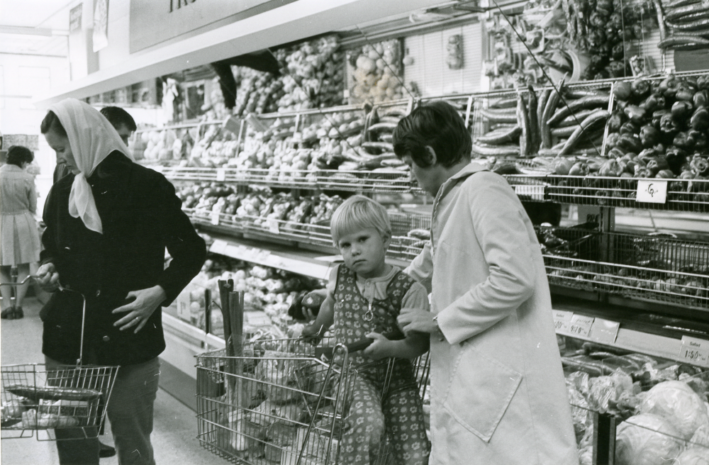 Interiör från Konsum på Allévägen i "Konsumhuset", nuvarande Torghuset. Kunder vid grönsaksdisken.

•Fotografiet ingår i bildserien ”Vardagsliv i Vallentuna kommun” av Rachael Gough-Azmier & Gunilla Blomé, Haga Studios HB.