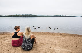 Två kvinnor som sitter på en sandstrand