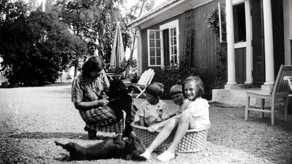 Elsa Tiberg köpte Bällsta gård och drev pensionatsverksamhet på gården 1928 till 1933, då hon startade Vallbostrands vårdhem.  Utanför flygeln sitter Gunnel Tiberg, gift med Elsas bror David, tillsammans med barnen Ulf,Björn och Mona samt hundar.  Barnen sitter i hundkorgen