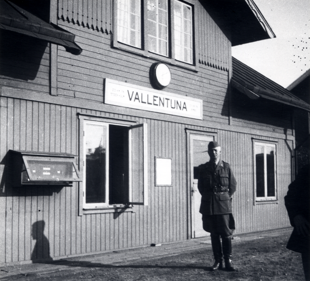 Vallentuna järnvägsstation under andra världskriget? En man klädd i uniform står framför stationshuset
