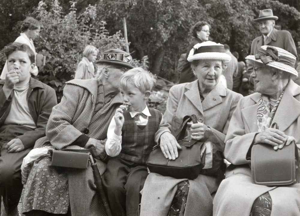 Vallentuna kyrkliga syförening håller auktion vid sommarfesten i Vallentuna prästgård. Kyrkoherde Sven Vängby är auktionsförrättare och initiativtagare, skrivare John Edman. Överst t h står tegelfabrikör A W Lundqvist.  Andra dam från höger är fru Arvida Malmberg, Ekebydal, med dottersonen Mats Sundin bredvid sig