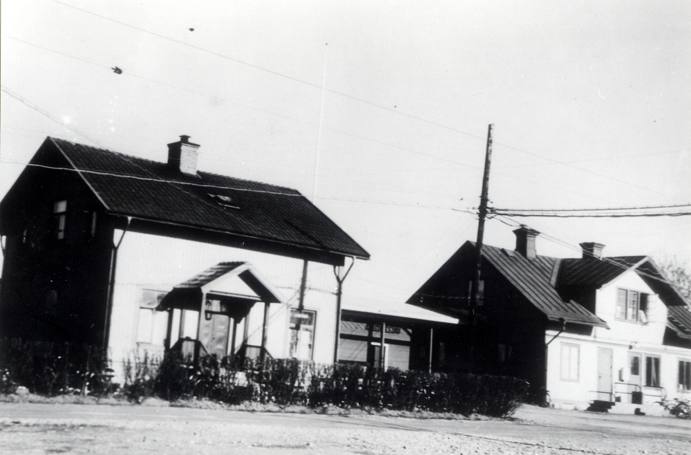 Vallentuna järnvägsstation sedd från baksidan med Järnvägsrestaurangen Flugan t v.  Mellan husen syns ett godsmagasin.  K S Karlssons smidesverkstad låg också på andra sidan spåren, den revs 1955