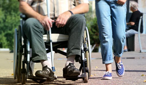 En rullstolsburen sida vid sida med en kvinna som är ute och går