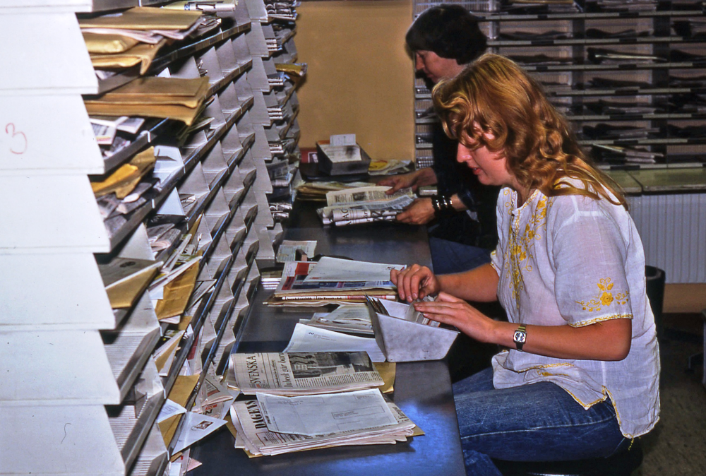 En arbetsdag med lantbrevbärare Mikael Mattsson. Sortering av post på brevbärarexpeditionen på Olsborgsvägen;  I förgrunden lantbrevbärare Rosemarie Bylund (bott i Husa) och i bakgrund lantbrevbärare Berit Testor (från Sollentuna) som ställer posten efter körordning, på brevbärarexpeditionen på Olsborgsvägen. Brevbärarexpeditionen revs 2009.