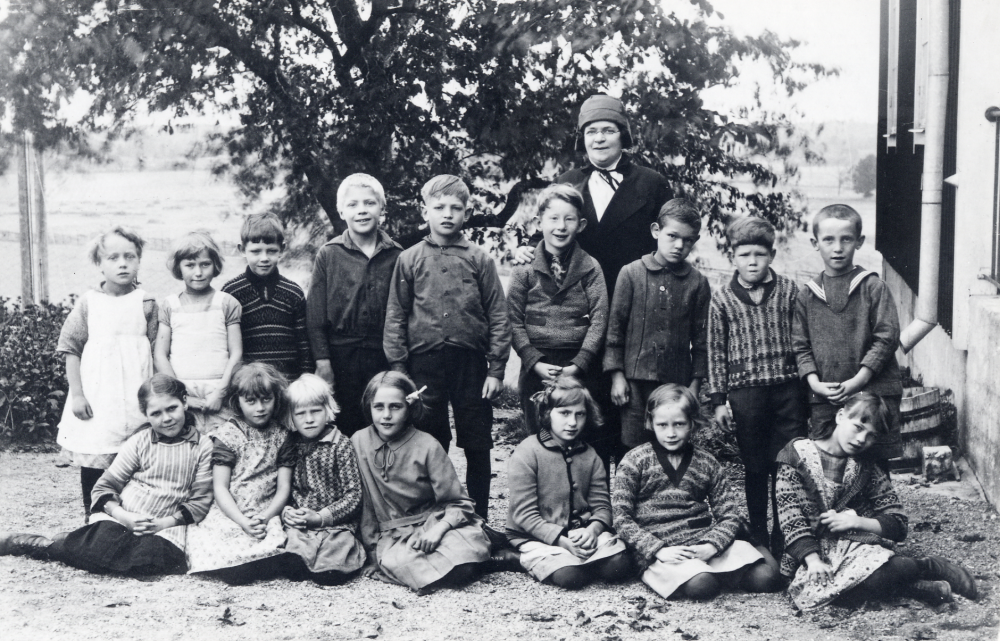 Lärarinnan  Ida Solem  tillsammans med skolbarnen utanför  Angarns kyrkskola  Stående fr v: okänd,  Aina Lindersson,  okänd, okänd,  Yngve Jansson,  Henry Eriksson,  Evert Andersson,  Verner Axén,  Bertil Jansson.  Sittande fr v: okänd,  Ulla Johansson,  Majsie Jansson,  Rakel Axén,  Greta Svensson,  Gunnel Johansson och  Astrid Lindersson