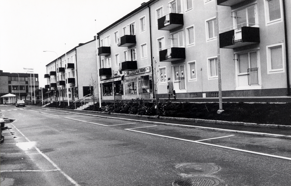 Centralvägen med affärer på höger sida, i huset t h Vallentuna sport och fritid och Vallentuna färg. Trottaren har just byggts om och Centralvägen blivit smalare till förmån för plantering och gång-cykelbana
