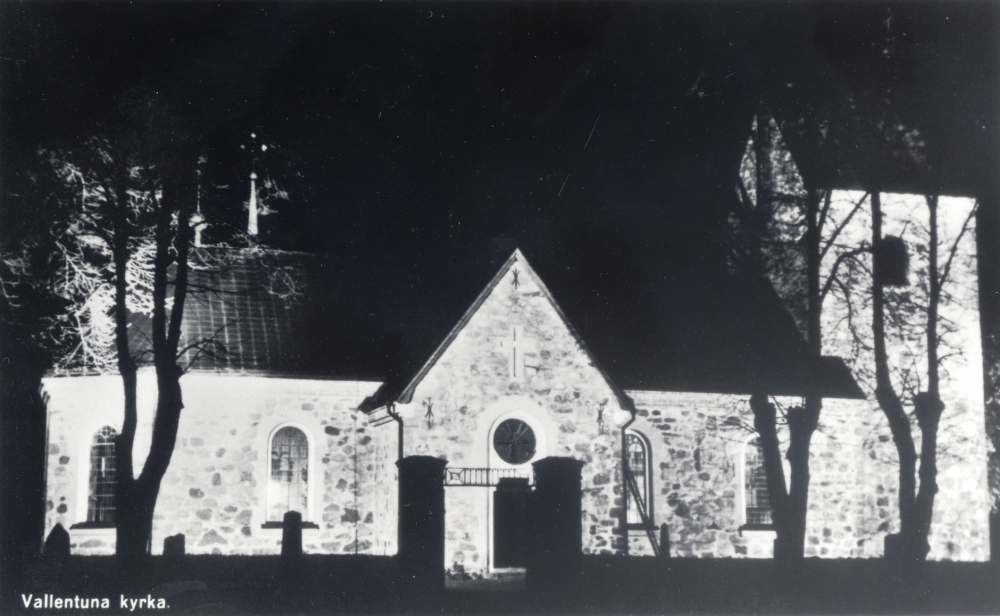 Vallentuna kyrka sedd från norr, fasadbelyst under dygnets mörka timmar