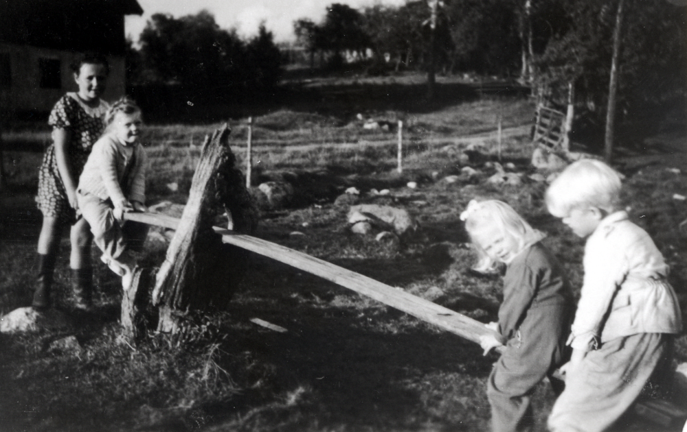 Gungbräda på Tjusta gård .  På vänster sida sitter Christina Helgöstam, dotter till gårdens ägare Hanna och Seth Helgöstam, och Malin Ask.  På höger sida sitter Britta och Anders Ask.  Barnen Ask är sommarbarn på gården