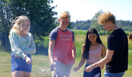 Fyra ungdomar som står och grillar