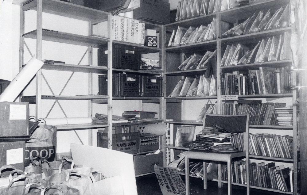 Vallentuna bibliotek på Allévägen. I hallen bland kontorsrummen är hyllor uppställda med material från barnavdelningen, backar med färger och kritor, diabildserier och bilderböcker