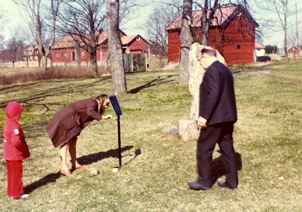 Lillian Glav och Thure Rudäng sätter upp nya skyltar och målar stolpen vid en runsten på planen utanför Lingsbergs gård på en inspektionsresa med skyltning av fornminnen i kommunen. Gustaf Åkerblom var också med på resan
