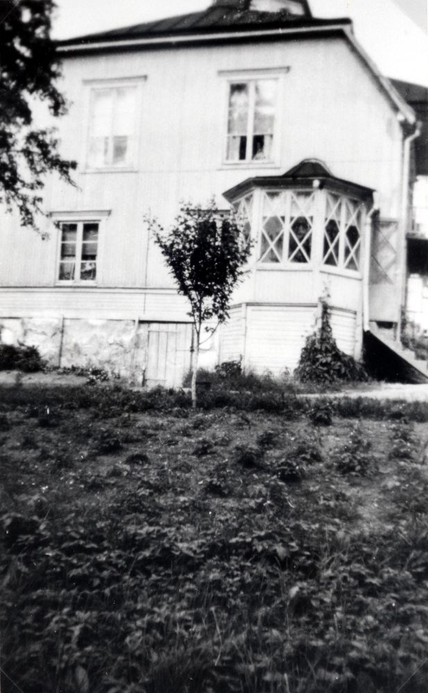 Ekskogens gård med glasveranda på mangårdsbyggnadens vänstra sida.  Lushuset byggdes ca 1905 av dåvarande ägaren Selma Gustavsson, det sägs att hon beundrade tornet på Backa gård och byggde ett liknade 1912 på sin egen huvudbyggnads tak.  Köksingången t v om verandan syns den nycementerade kökstrappan