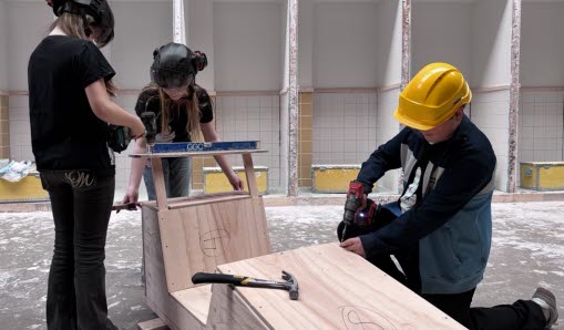 Tre barn arbetar med en lådbil i trä.