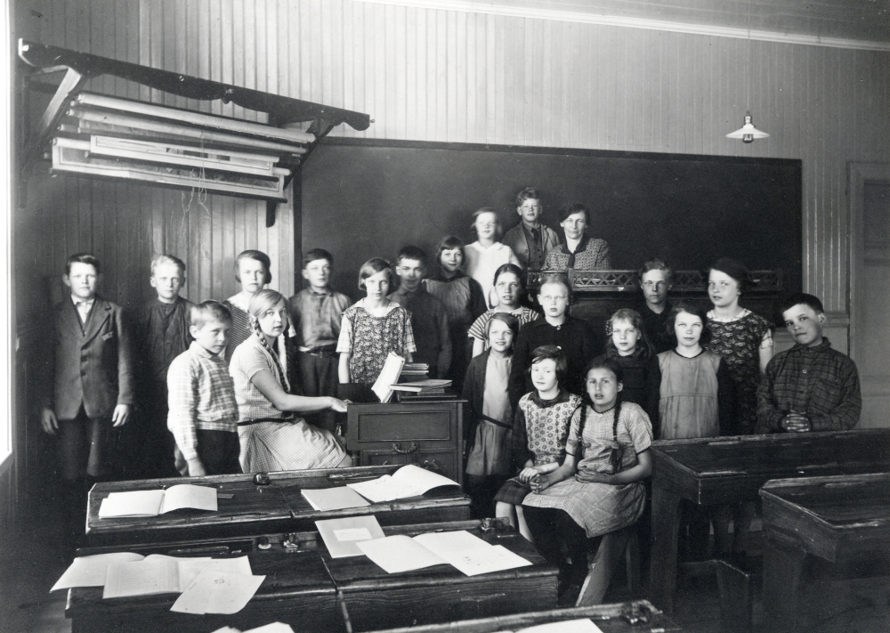 Angarns kyrkskola. Skolfotografi från skolsalen. T v om orgeln och ovanför katedern: Olle Eriksson Alby, Sixten Jansson Lövlund, Harry Johansson Rävsta, Ingrid Johanson Rävsta, vid orgeln Cissi Olsson Åsta, Gösta Åkersten Ö Båtmanstorp, Gunhild Törnkvist Damsta, Olof Eriksson Åsta, Rakel Åkersten Ö Båtmanstorp, Britt Jansson Lövlund, Nils Andersson Lundby och lärarinnan Elna Andersson. T h om orgeln nedanför katedern: Anna-Lisa Gustavsson Alby, Helmy Nilsson Rörby, Eivor Andersson Lundby, Anna Britta Karlsson Lundhem, Inga Lisa Eriksson Örsta, Karin Norman Sofieberg, Einar Andersson Veda, Eivor Eriksson Alby, Ingrid Törnkvist Damsta, och Hilding Eriksson Åsta Uppgiftslämnare: Elsa Malm, född Olsson, Cissi Pettersson, född Olsson, Hilding Eriksson och Inga Lisa Andersson född Eriksson