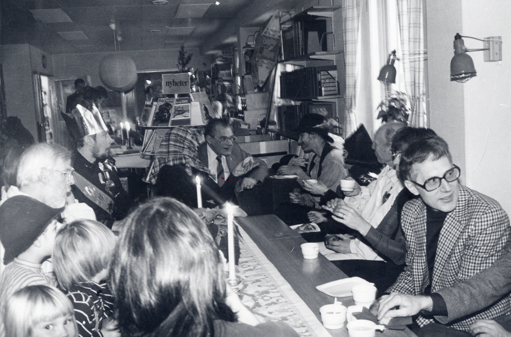 Vallentuna staffanssångare  samlade runt kaffebordet i  Vallentuna bibliotek  efter att ha sjungit staffans- och stjärngossesånger för personal från kommunen vid  luciafirande  Fr v runt bordet sitter okänd, okänd, okänd,  Calle Rahmqvist   Lasse Berglund  okänd skymd,  Gunnar Hillbo   Ulla-Britt Kvarnestam?  kommunalrådet  Carl-Eric Wikström   Eva Rahmqvist   Gun Hillbo   Evert Lillefors  och okänd