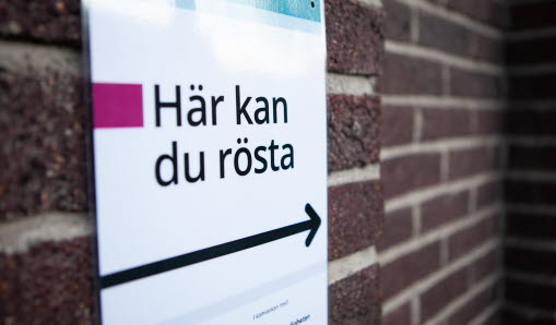 Poster på tegelvägg, med ikon av en pil med text Här kan du rösta.